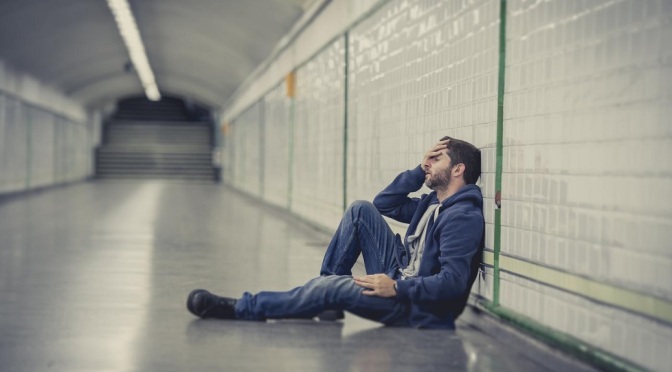 man-lost-in-depression-sitting-on-ground-street-subway-tunnel